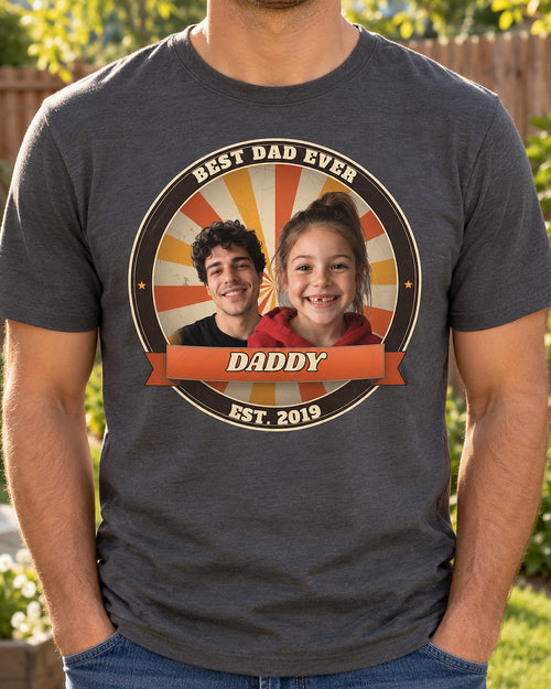Man wearing a charcoal Dad Est. photo badge t-shirt with two kids' faces in a retro sunburst badge, the name Daddy, Best Dad Ever and Est. 2019