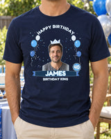 Navy birthday portrait shirt with a crown, blue and silver balloons, age 40 badge and the name James beside a backyard party table.