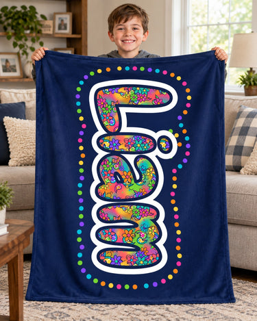 Boy holding up a navy blue custom name blanket reading Liam in bright doodle bubble letters