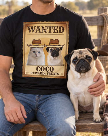 Adult cropped below the chin with a fawn pug at a ranch bench, wearing a black Wanted pet photo shirt featuring that same pug and a white cat in cowboy hats.