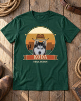 Forest green Desert Sunset pet photo tee laid on barn wood beside rope, a plain leather belt and cowboy boots, with a cowboy-hatted husky and the name KODA.