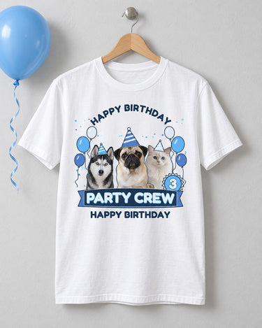 White pet birthday tee on a wooden hanger with three pets in striped party hats, blue and silver balloons, age 3 and Party Crew lettering.