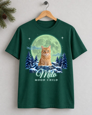 Forest green custom cat moon t-shirt on a wooden hanger with an orange tabby cat under an aurora-green moon and the name Milo