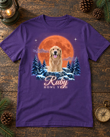 Purple pet moon t-shirt laid flat on a dark wooden table with a camping lantern, pine cones and a brass compass, a golden retriever under a blood moon with the name Ruby