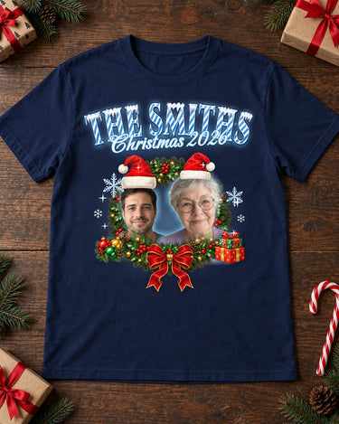 Navy face Christmas t-shirt laid flat with gift boxes, pine branches and a candy cane, two faces in Santa hats in a wreath with icy blue lettering