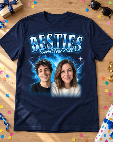 Navy custom face collage t-shirt laid flat on an oak table with birthday confetti, sunglasses and a gift, two faces in an ice blue glow and the name Besties