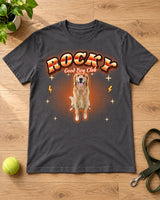 Charcoal pet bootleg t-shirt laid flat on a wooden floor with a dog leash and a tennis ball, the name Rocky and a golden retriever