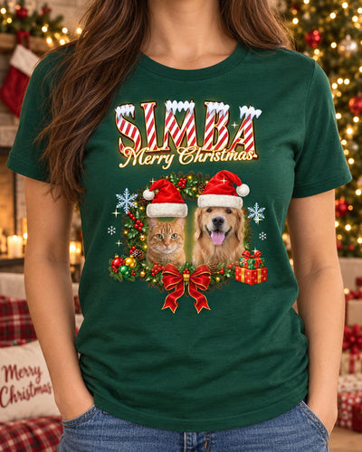 Woman wearing a forest green custom pet Christmas t-shirt with the name Simba in candy-cane lettering and a dog and a cat in Santa hats inside a holly wreath