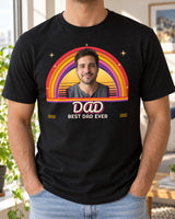 Black custom retro photo shirt worn in a bright apartment, with a portrait above a striped sunset, red-to-purple rainbow arcs and DAD in groovy script.
