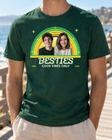 Forest green retro photo shirt worn on a sunny boardwalk, showing two portraits, green and yellow sunset arcs and BESTIES with Good Vibes Only underneath.
