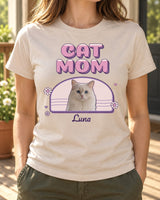 Natural cat mom photo tee on a sunlit porch, showing CAT MOM in retro bubble letters, Luna the white cat inside a berry arch and a small script name.
