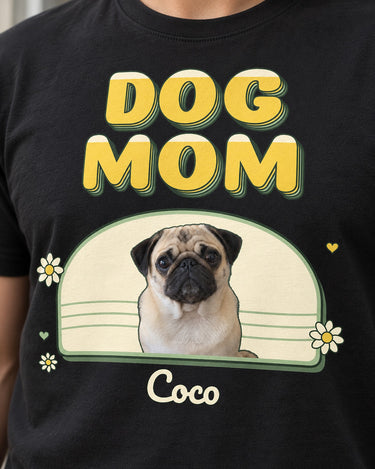 Close-up of a black DOG MOM pet photo shirt with three-layer retro lettering, a pug in a cream arch, green edging, yellow daisies and the script name Coco.