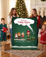 Mommy's Little Elves personalized blanket with kids names held by mom and her children by the fireplace