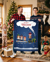 Daddy's Elf Crew personalized blanket with kids names held by dad and son in a cozy Christmas living room