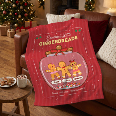 Personalized gingerbread blanket draped over a leather sofa next to hot cocoa and cookies