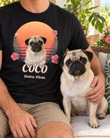Black tropical pet photo T-shirt worn on a plant-filled patio beside a fawn pug, with the same pug portrait, flower lei and Coco name in the print.