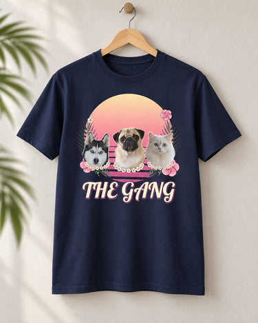 Navy Aloha pet photo tee on a wooden hanger, with three pets wearing flower leis against a Flamingo Pink sunset and The Gang in outlined script.