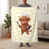 Personalized Highland cow chef blanket in lemon cream held up in a living room, with the name Emma repeated in soft waves
