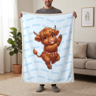Personalized Highland cow dancing blanket in baby blue held up in a living room, with the name Emma repeated in soft waves