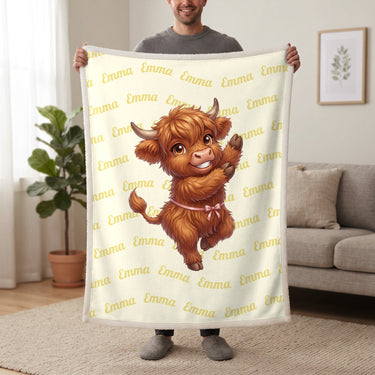 Personalized Highland cow dancing blanket in lemon cream held up in a living room, with the name Emma repeated in soft waves