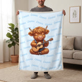 Personalized Highland cow guitar blanket in baby blue held up in a living room, with the name Emma repeated in soft waves