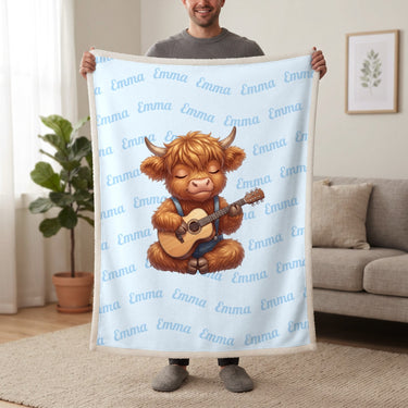 Personalized Highland cow guitar blanket in baby blue held up in a living room, with the name Emma repeated in soft waves