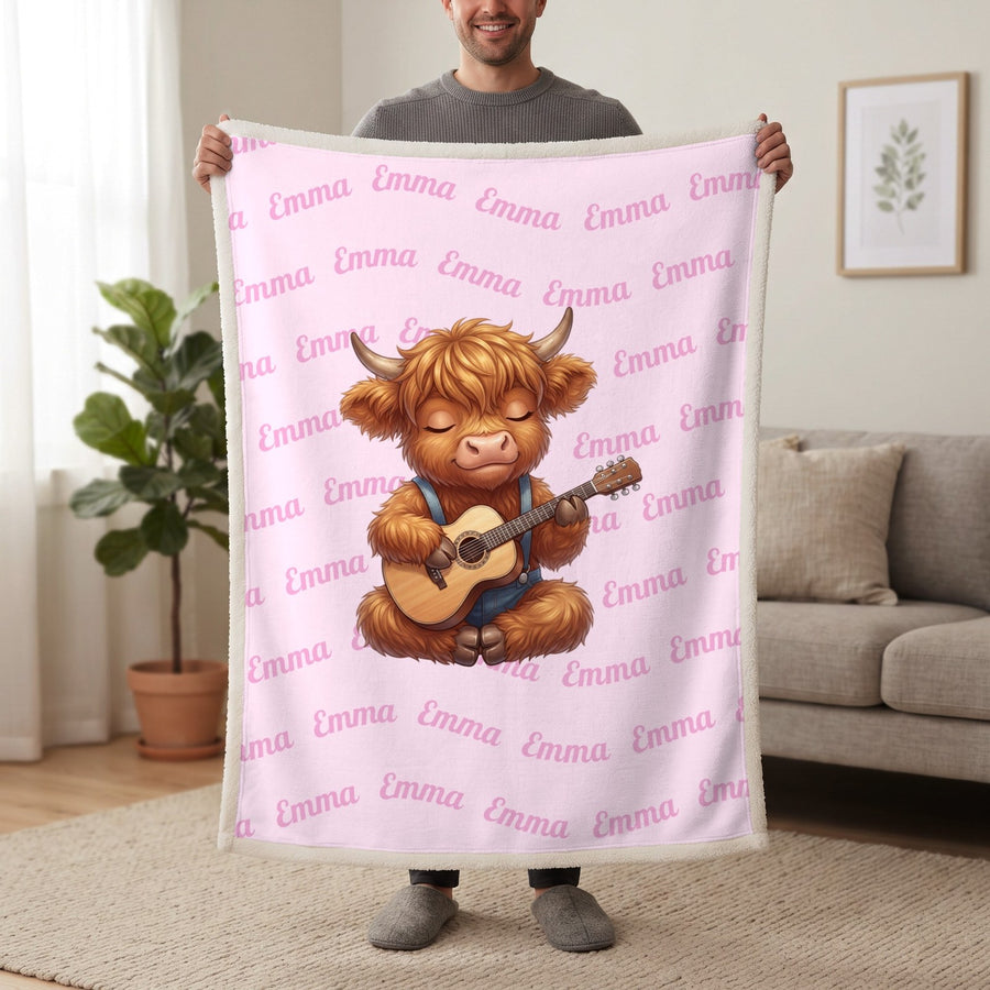 Personalized Highland cow guitar blanket in cotton pink held up in a living room, with the name Emma repeated in soft waves