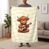 Personalized Highland cow guitar blanket in lemon cream held up in a living room, with the name Emma repeated in soft waves