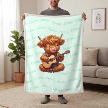 Personalized Highland cow guitar blanket in mint held up in a living room, with the name Emma repeated in soft waves