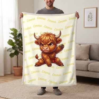Personalized Highland cow karate blanket in lemon cream held up in a living room, with the name Emma repeated in soft waves