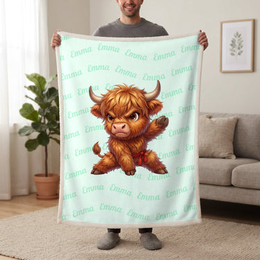Personalized Highland cow karate blanket in mint held up in a living room, with the name Emma repeated in soft waves