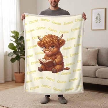 Personalized Highland cow reading blanket in lemon cream held up in a living room, with the name Emma repeated in soft waves