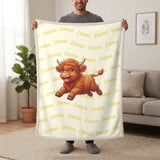 Personalized Highland cow running blanket in lemon cream held up in a living room, with the name Emma repeated in soft waves
