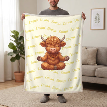 Personalized Highland cow yoga blanket in lemon cream held up in a living room, with the name Emma repeated in soft waves
