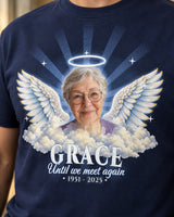 Close-up of the print on a navy in loving memory t-shirt: a grandmother's photo, a silver halo, angel wings and clouds