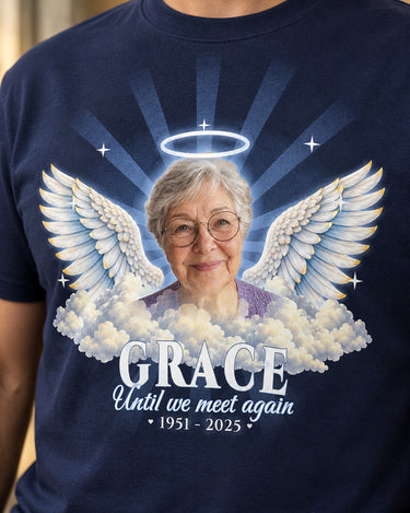 Close-up of the print on a navy in loving memory t-shirt: a grandmother's photo, a silver halo, angel wings and clouds
