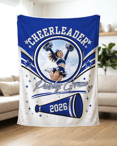 Custom cheerleader name and photo blanket held up in a bright living room to show the soft fleece and royal blue megaphone design