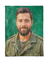Flat lay of a custom portrait blanket with an oil painted bearded man on emerald green brushstrokes and the name Daniel