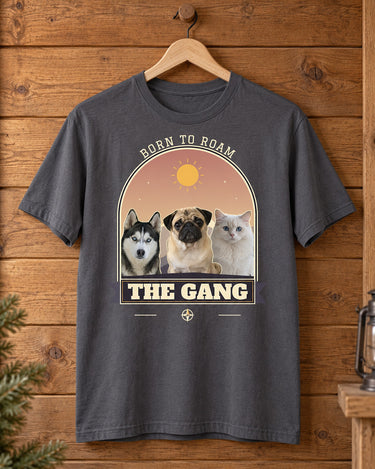 Charcoal pet adventure shirt on a wooden hanger, showing three pets in a muted purple mountain arch above a cream slab-serif nameplate reading The Gang.