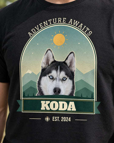 Close-up of the black mountain pet tee with Koda the husky, cream slab-serif lettering, green mountain layers, golden sun and a bordered arch.