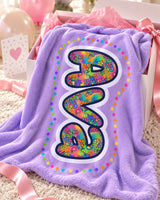 Lavender personalized name blanket reading Ava spilling out of a white gift box with pink tissue paper and a satin ribbon