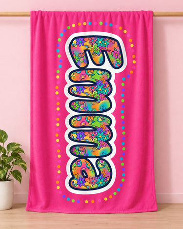 Hot pink custom name blanket reading Emma hanging from a wooden rod against a pastel pink wall