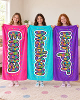 Three girls holding personalized doodle name blankets in hot pink, aqua and purple with the names Emma, Madison and Harper in bright bubble letters
