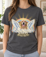 Woman wearing a charcoal pet memorial t-shirt with a golden retriever with angel wings and a halo over a rainbow and clouds, the name Daisy and the words Forever in my heart