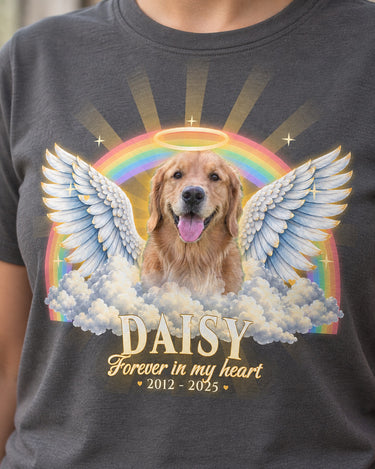 Close-up of the full-color print on a charcoal pet memorial t-shirt: a golden retriever with angel wings and a halo, a pastel rainbow, the name Daisy and the dates