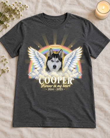 Dark heather pet memorial t-shirt laid flat on linen with white wildflowers and a candle, a husky with angel wings and the name Cooper with dates