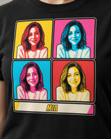 Close-up of a black pop art portrait tee showing four flat portrait tones, clear dark outlines, halftone dots and large comic name lettering.