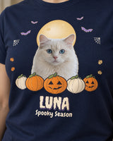 Close-up of a navy custom dog Halloween shirt with a white cat portrait, golden full moon, purple bats, carved pumpkins and the name LUNA.