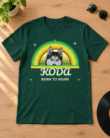 Forest green pet retro sunset t-shirt laid flat on an oak table with round sunglasses, a vinyl record and a plant, a husky in lemon-lime rainbow arcs with the name Koda