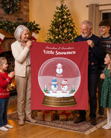 Personalized grandparents blanket with grandkids names, red snow globe design with little snowmen held up by grandma, grandpa and the grandkids by the Christmas tree